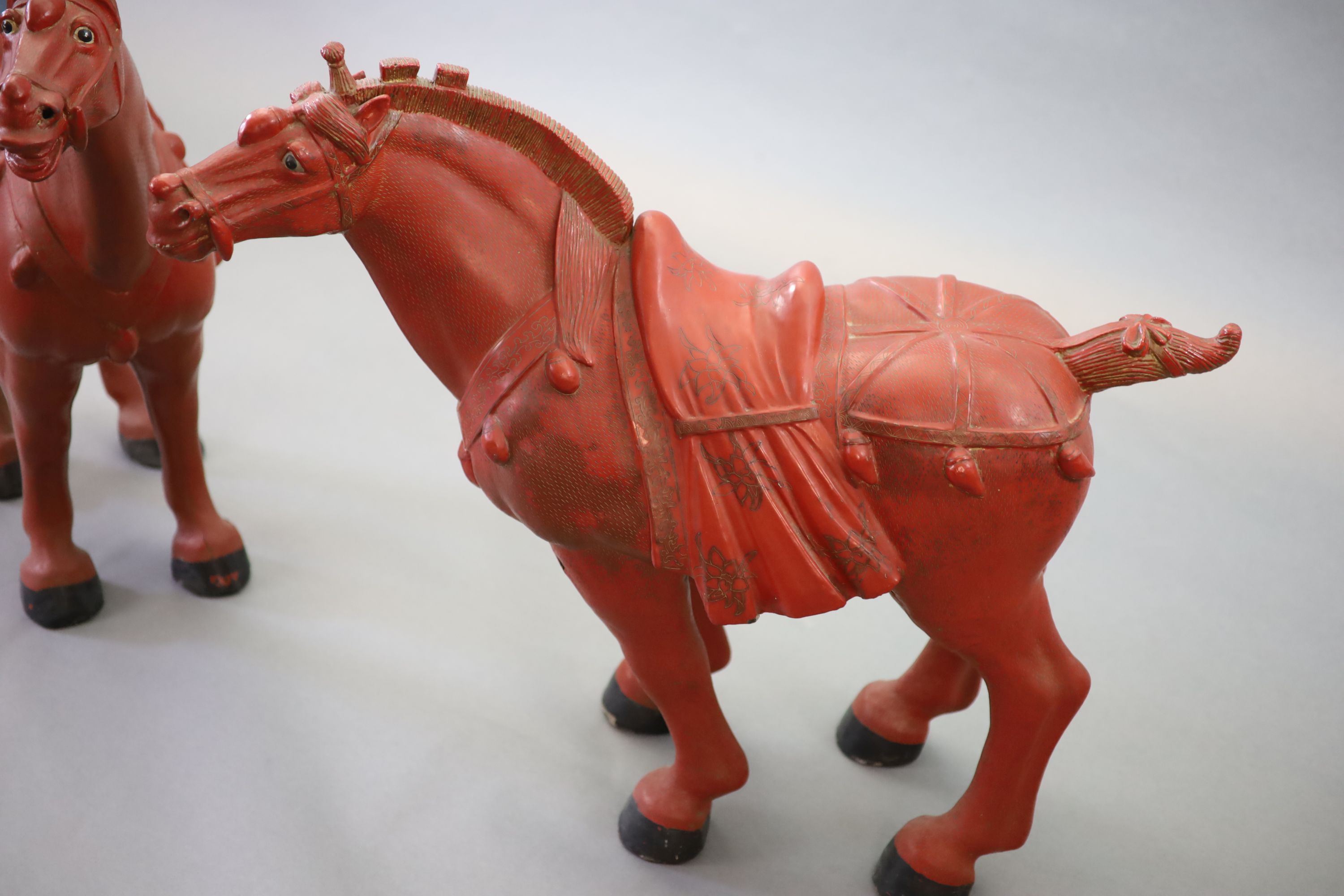 A pair of Chinese cinnabar lacquered horses with plinth stands